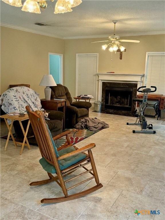 living room featuring ceiling fan, a textured ceiling, and crown molding