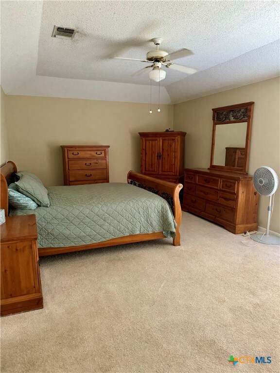 bedroom with ceiling fan, a textured ceiling, and light carpet