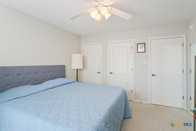 bedroom featuring multiple closets, ceiling fan, and light carpet