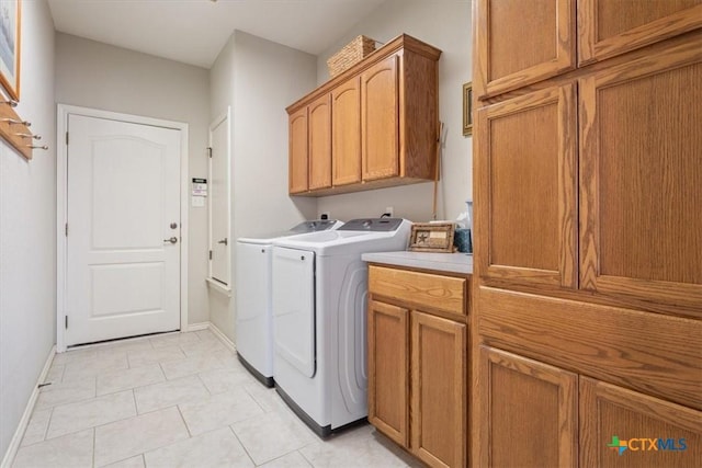 washroom with cabinets, light tile patterned flooring, and washing machine and clothes dryer