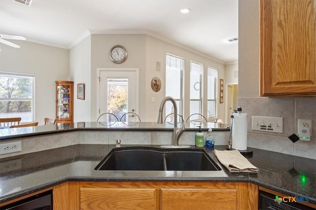 kitchen featuring backsplash, ornamental molding, sink, and dark stone counters