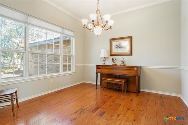 miscellaneous room featuring a healthy amount of sunlight, crown molding, light hardwood / wood-style floors, and a notable chandelier