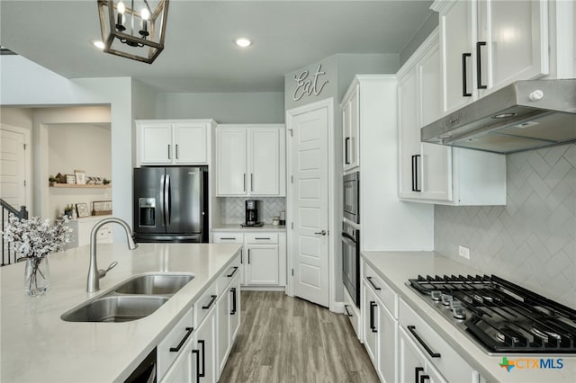 kitchen with white cabinets, a sink, light countertops, stainless steel appliances, and under cabinet range hood