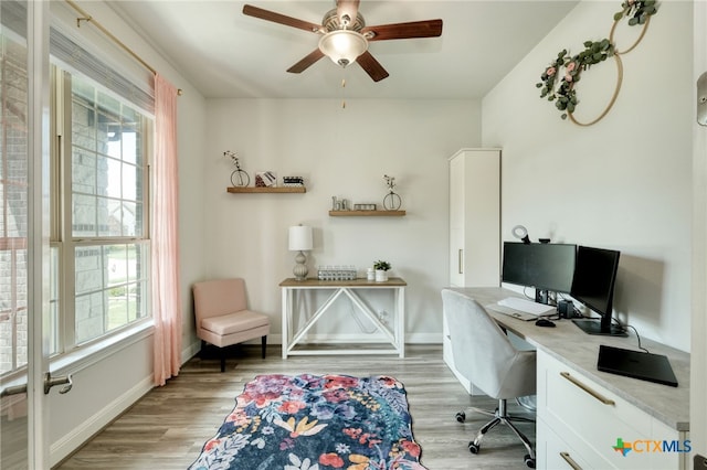 office space featuring baseboards, ceiling fan, and light wood-type flooring