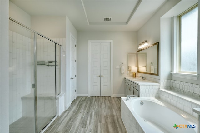 bathroom featuring a garden tub, visible vents, a stall shower, wood finished floors, and vanity