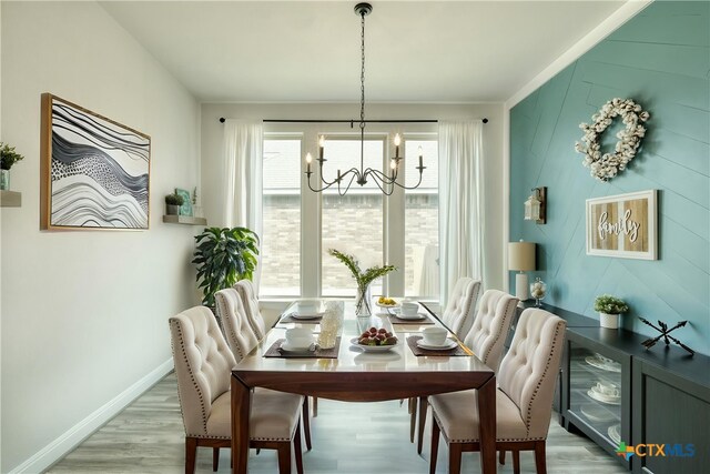 dining area featuring light wood-style floors, baseboards, and a notable chandelier