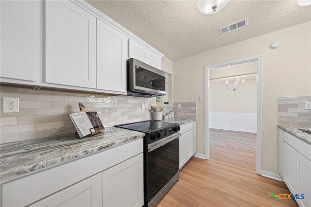 116 Spur Dr, Copperas Cove, TX 76522 - kitchen featuring electric range, stainless steel microwave, light wood-style flooring, white cabinetry, and a textured ceiling