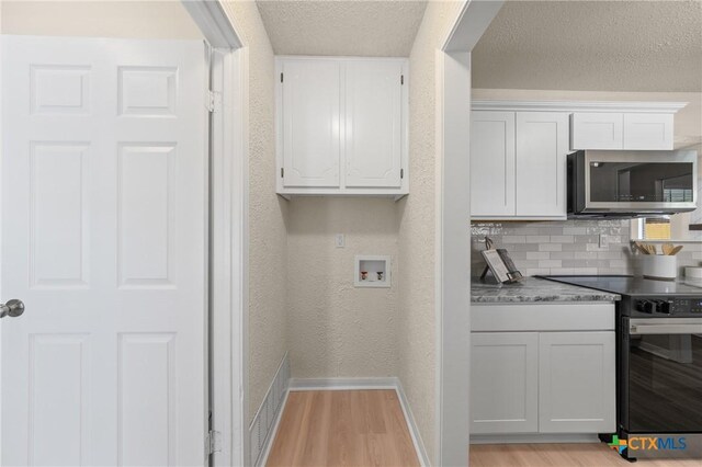 116 Spur Dr, Copperas Cove, TX 76522 - kitchen featuring stainless steel microwave, black / electric stove, light wood finished floors, white cabinetry, and tasteful backsplash