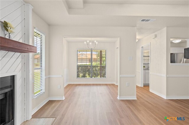 116 Spur Dr, Copperas Cove, TX 76522 - unfurnished living room with light wood-style flooring, a fireplace with flush hearth, and a chandelier