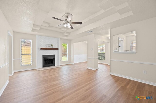 116 Spur Dr, Copperas Cove, TX 76522 - unfurnished living room featuring a raised ceiling, light wood finished floors, a ceiling fan, and a fireplace