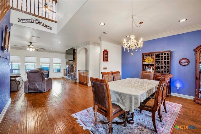 dining area with arched walkways, wood finished floors, a chandelier, ornamental molding, and baseboards