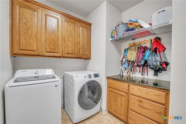 washroom with independent washer and dryer, cabinet space, and light tile patterned flooring