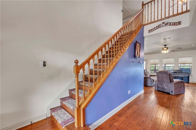 staircase featuring ceiling fan, baseboards, and hardwood / wood-style flooring