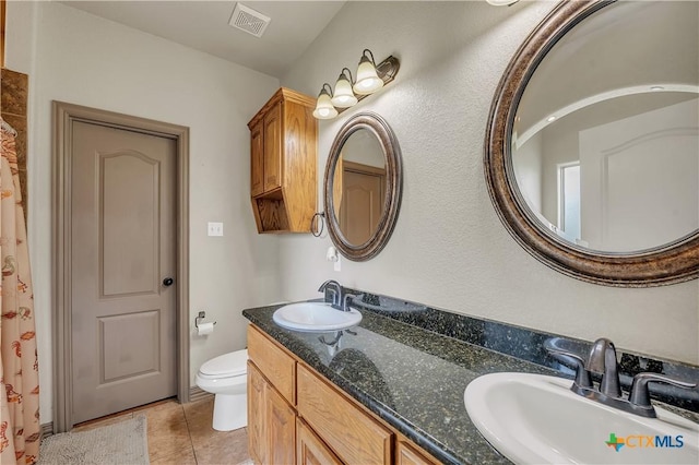 bathroom featuring toilet, tile patterned floors, and double vanity