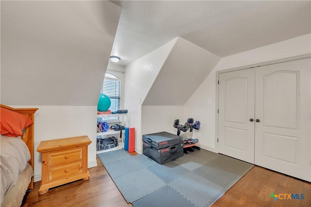bedroom featuring wood finished floors, vaulted ceiling, and a closet