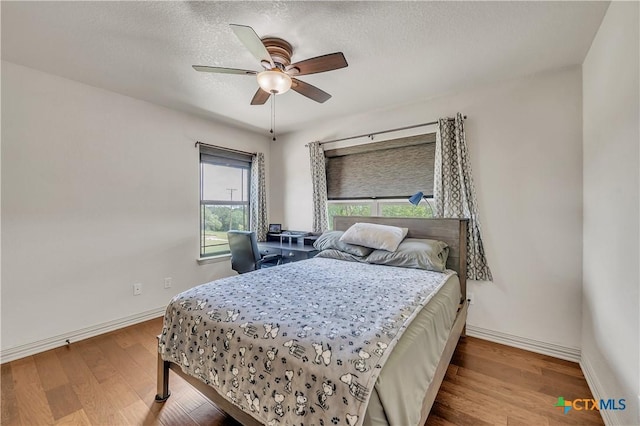 bedroom featuring wood finished floors, baseboards, a textured ceiling, and ceiling fan