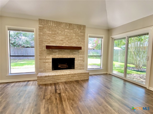 507 Santa Fe, Victoria, TX 77904 - unfurnished living room featuring wood finished floors, plenty of natural light, a brick fireplace, and lofted ceiling