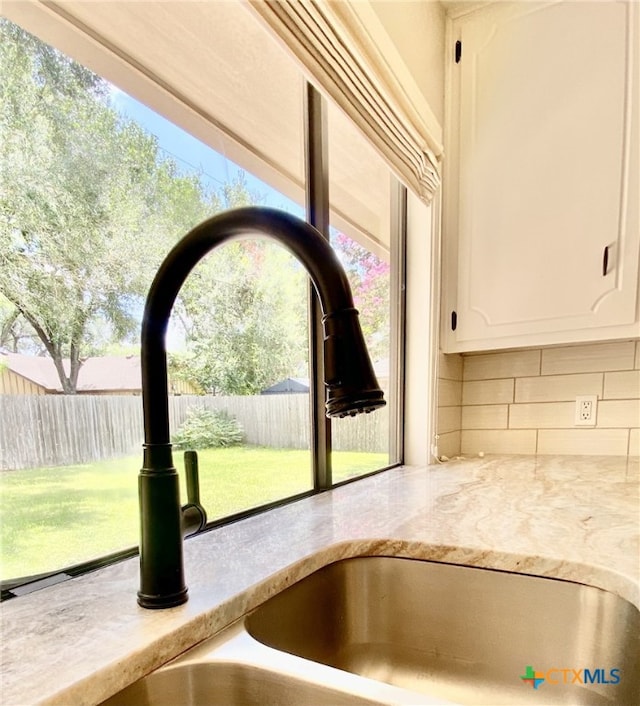 507 Santa Fe, Victoria, TX 77904 - kitchen view of decorative backsplash, white cabinetry, and light stone counters