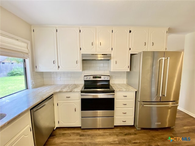 507 Santa Fe, Victoria, TX 77904 - kitchen with appliances with stainless steel finishes, under cabinet range hood, white cabinets, dark wood-type flooring, and tasteful backsplash