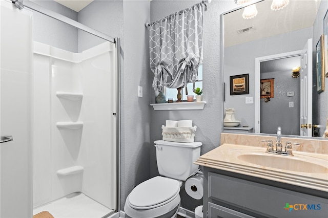 bathroom with a shower stall, vanity, visible vents, toilet, and a textured wall