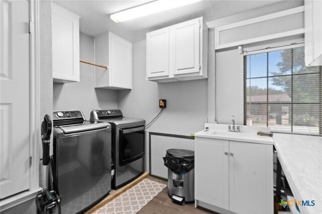 washroom with wood finished floors, independent washer and dryer, a sink, and cabinet space