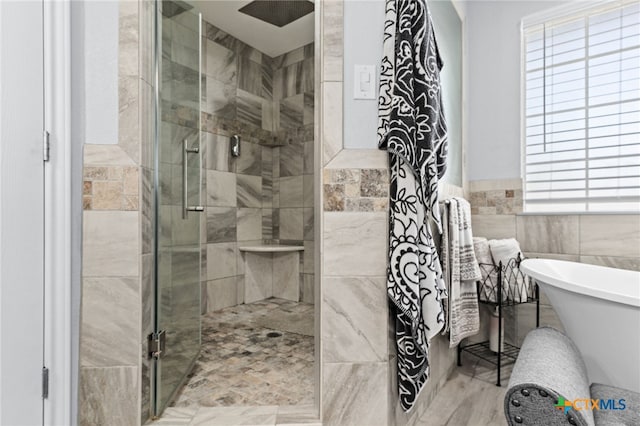full bathroom featuring a shower stall, a soaking tub, wainscoting, and tile walls