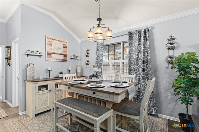 dining space featuring ornamental molding, wood finished floors, lofted ceiling, baseboards, and a notable chandelier