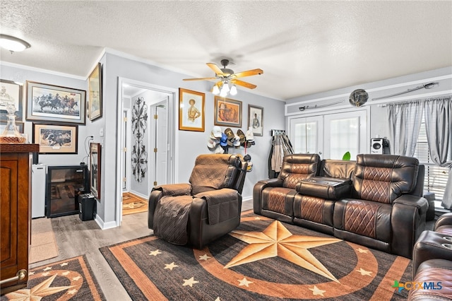 living area featuring light wood finished floors, a textured ceiling, a ceiling fan, and a healthy amount of sunlight