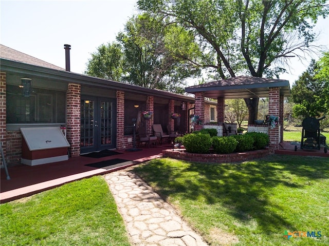 exterior space with french doors, a yard, and brick siding
