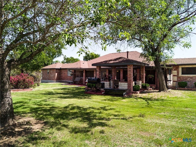 rear view of property featuring a yard and brick siding