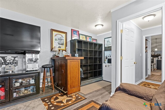 interior space featuring a textured ceiling, wood finished floors, and ornamental molding
