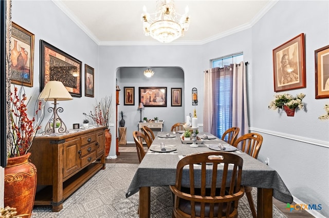 dining space with baseboards, an inviting chandelier, ornamental molding, light wood-style floors, and arched walkways