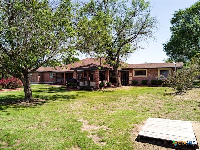 rear view of property featuring brick siding and a lawn