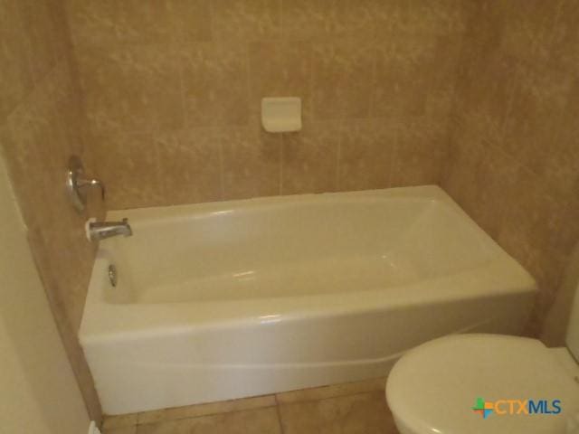 bathroom with tile patterned flooring, toilet, and a bath