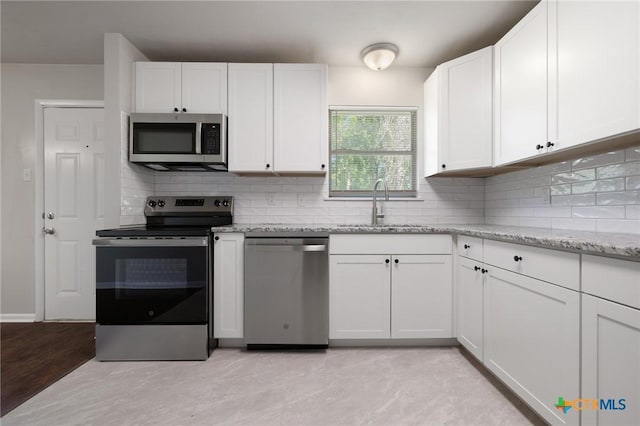 716 S 3rd St, Copperas Cove, TX 76522 - kitchen with appliances with stainless steel finishes, white cabinetry, light stone counters, decorative backsplash, and light wood finished floors