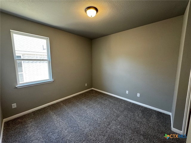 spare room featuring a textured ceiling and dark carpet