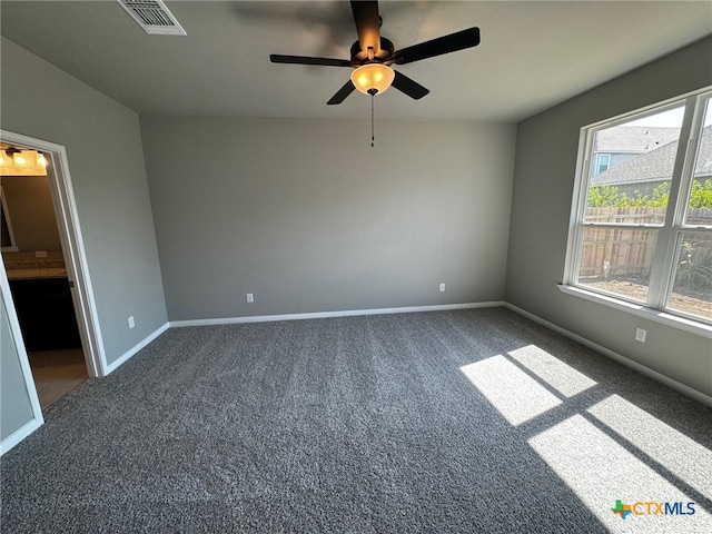 unfurnished room with dark colored carpet and ceiling fan