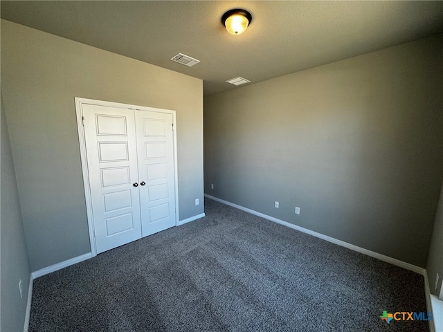 unfurnished bedroom with a closet and dark carpet