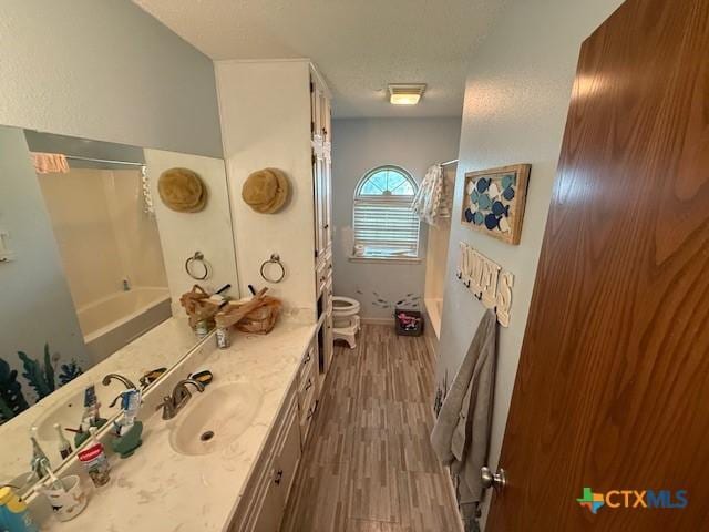 410 Phoenix Dr, Temple, TX 76504 - bathroom featuring vanity, wood finished floors, shower / bathtub combination with curtain, and a textured ceiling