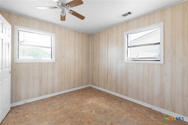 1202 S 3rd St, Copperas Cove, TX 76522 - spare room with ceiling fan, tile patterned floors, wooden walls, and a textured ceiling