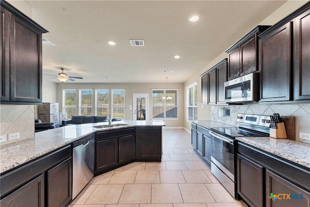 kitchen with sink, pendant lighting, decorative backsplash, ceiling fan with notable chandelier, and appliances with stainless steel finishes