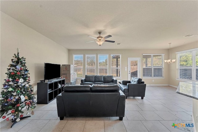 living room featuring light tile patterned floors, ceiling fan with notable chandelier, a textured ceiling, and a wealth of natural light