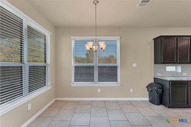 unfurnished dining area featuring light tile patterned floors and a chandelier