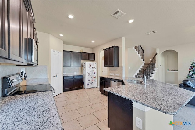 kitchen with light stone countertops, sink, backsplash, light tile patterned flooring, and appliances with stainless steel finishes