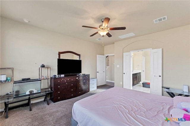 bedroom featuring ceiling fan, light colored carpet, and connected bathroom