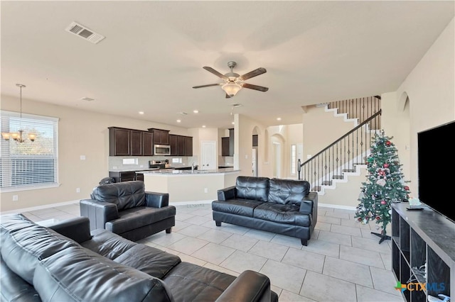 living room with light tile patterned flooring and ceiling fan with notable chandelier