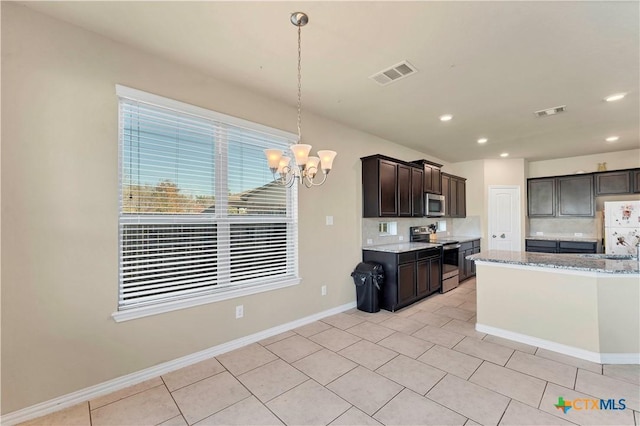 kitchen with backsplash, light stone counters, dark brown cabinets, stainless steel appliances, and decorative light fixtures