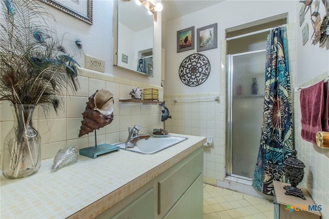 1105 E Robertson Ave, Copperas Cove, TX 76522 - bathroom featuring a shower stall, vanity, tile patterned flooring, tile walls, and a wainscoted wall