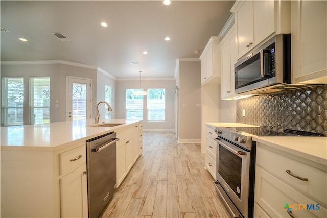 kitchen with a sink, tasteful backsplash, appliances with stainless steel finishes, and ornamental molding