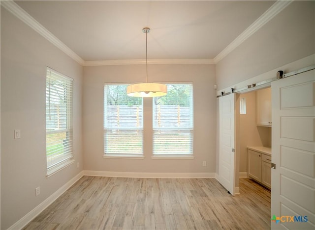 unfurnished dining area featuring a barn door, crown molding, baseboards, and light wood finished floors